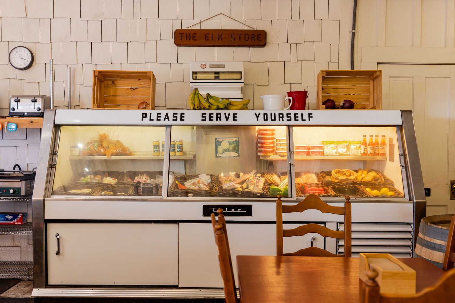 Rustic bakery counter with self-serve pastry displays and white tiled walls.