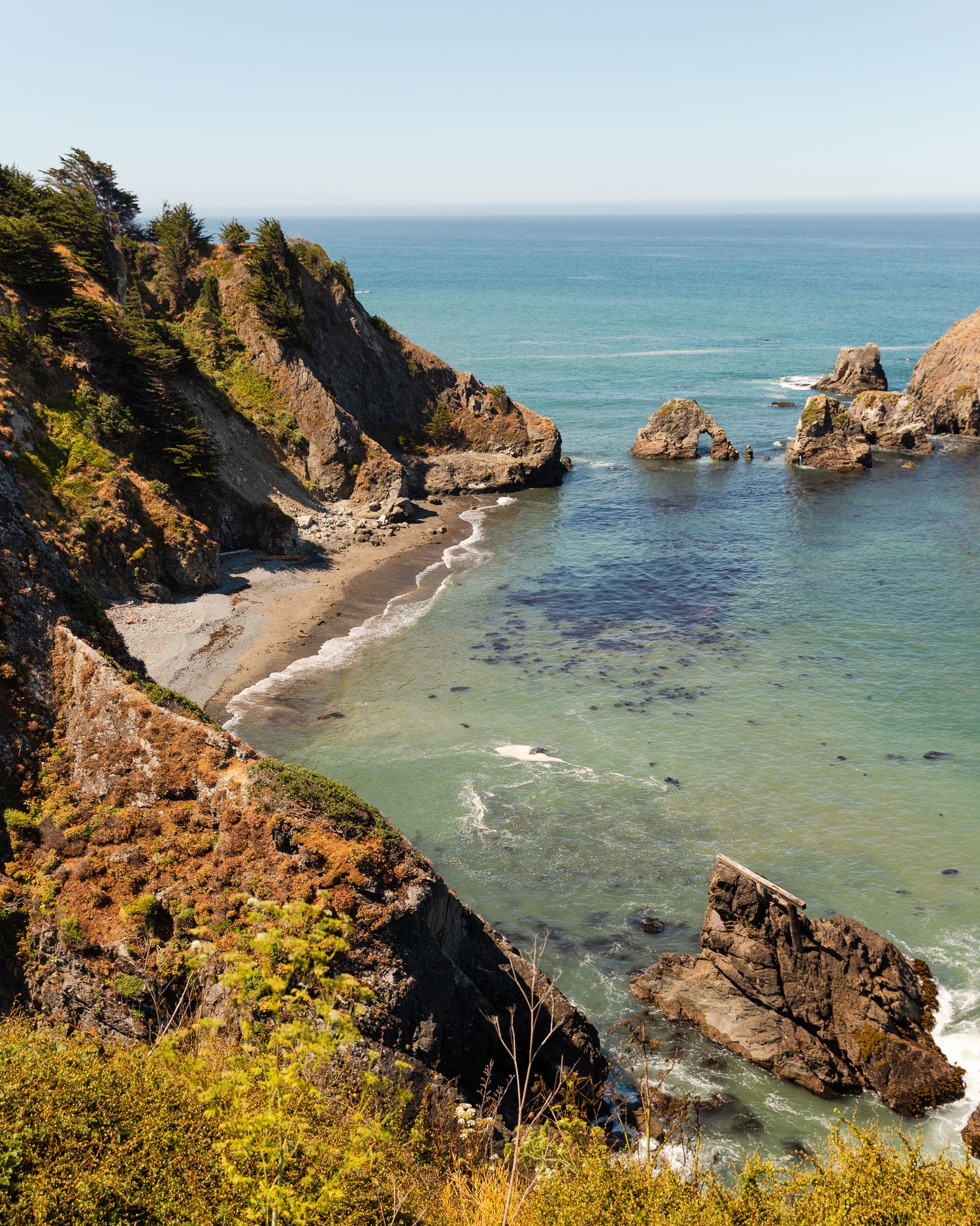 Dramatic coastal view of rocky cliffs and turquoise waters along a rugged shoreline.