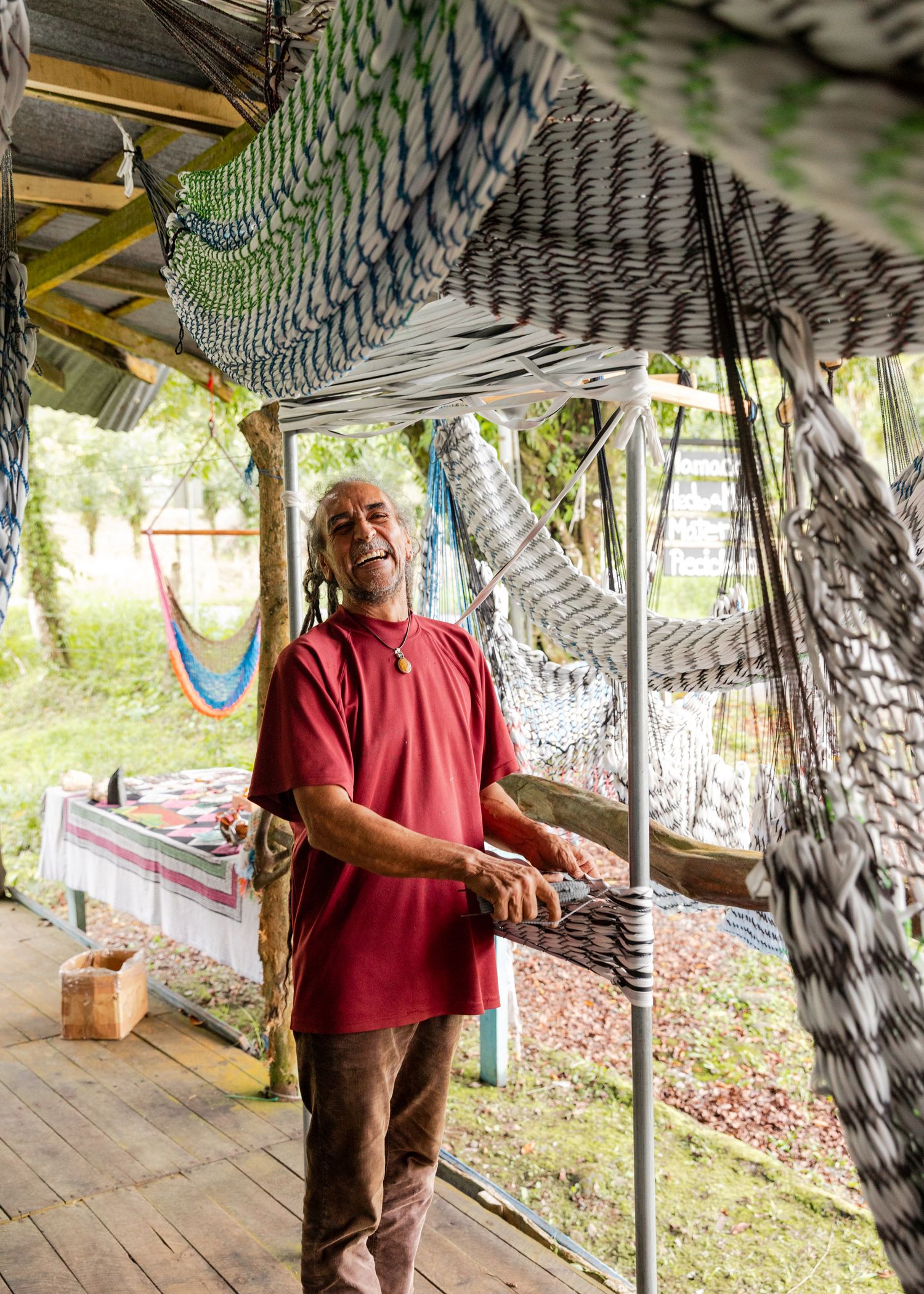 Person in red shirt and brown pants stands inside a covered walkway with artistic wall decorations.
