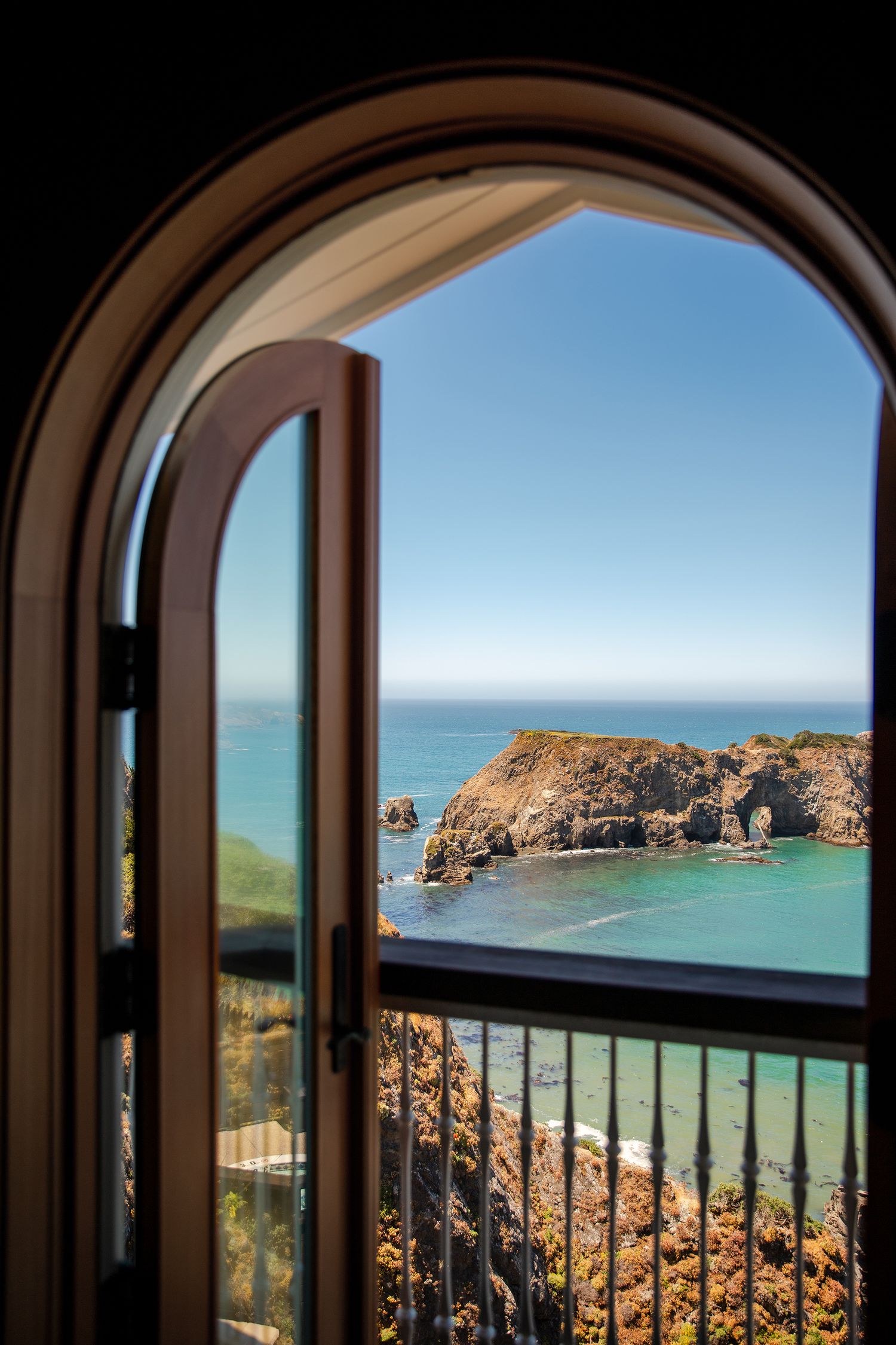 Open arched window revealing stunning turquoise coastal bay. Vail, Colorado hospitality and travel photographer.