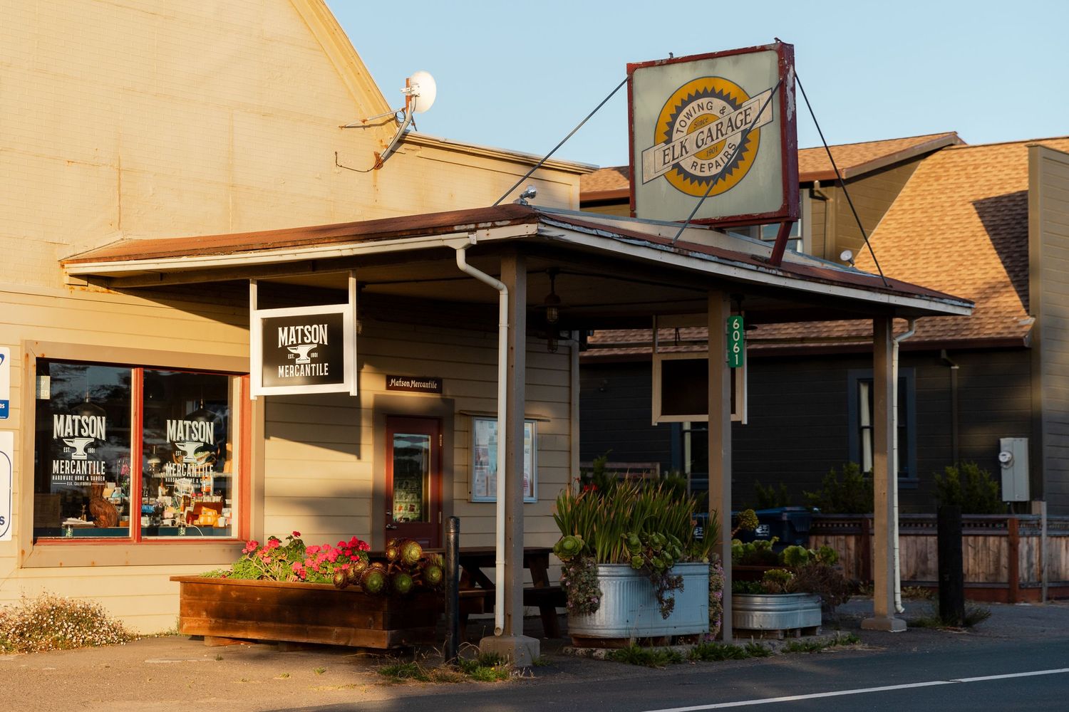 Small town storefronts and local businesses line a quiet street at sunset.