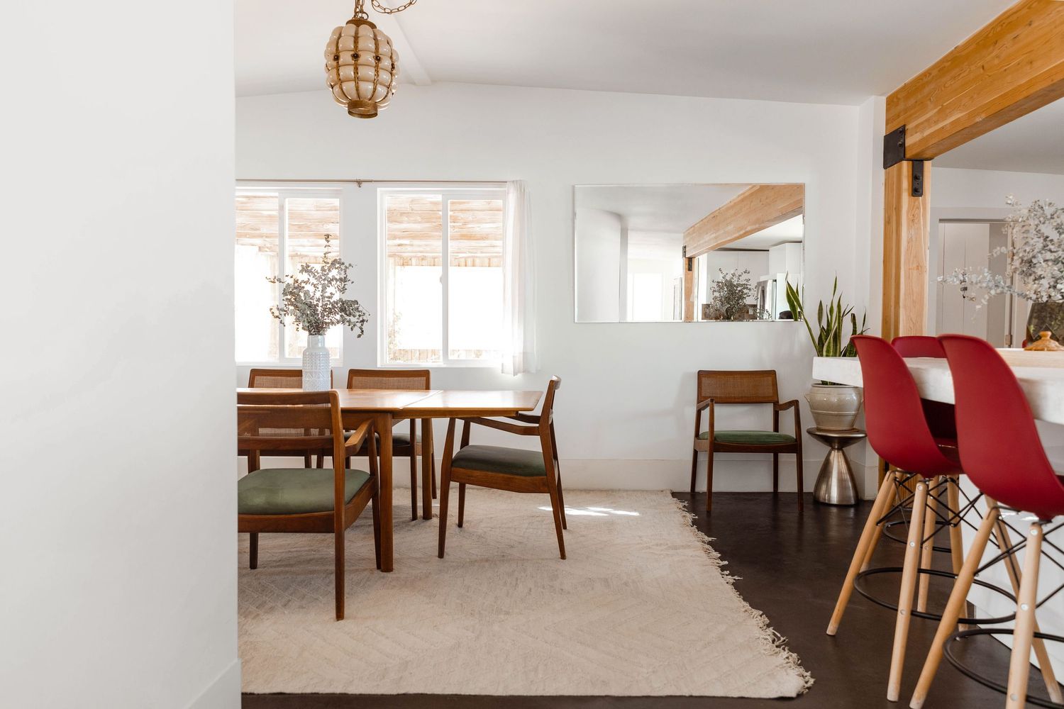 Modern dining room with mid-century furniture, wooden chairs, and a pendant light fixture.