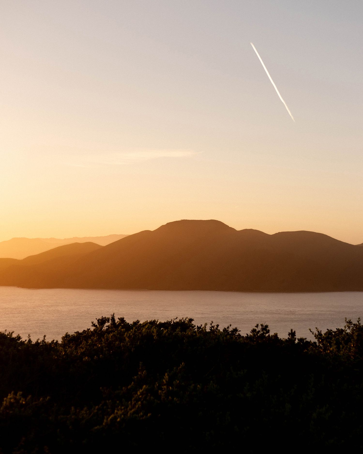 Silhouetted mountain range against an orange sunset sky.