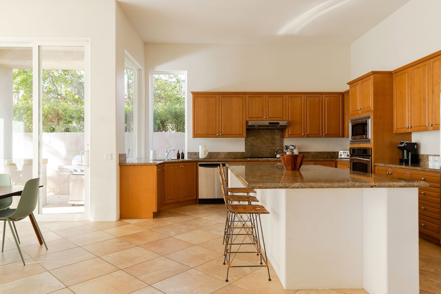 Spacious kitchen with honey oak cabinets, granite countertops, center island, and tile flooring.