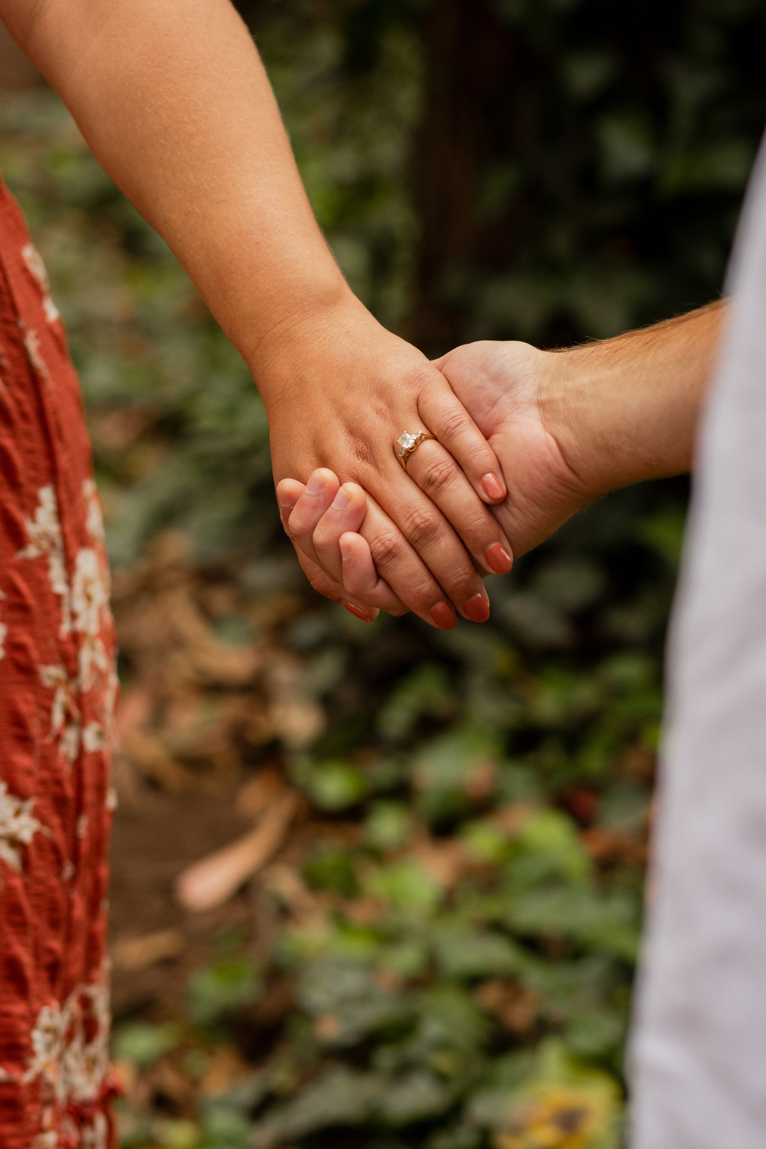 Close-up series of hands holding each other tenderly against a blurred natural background.