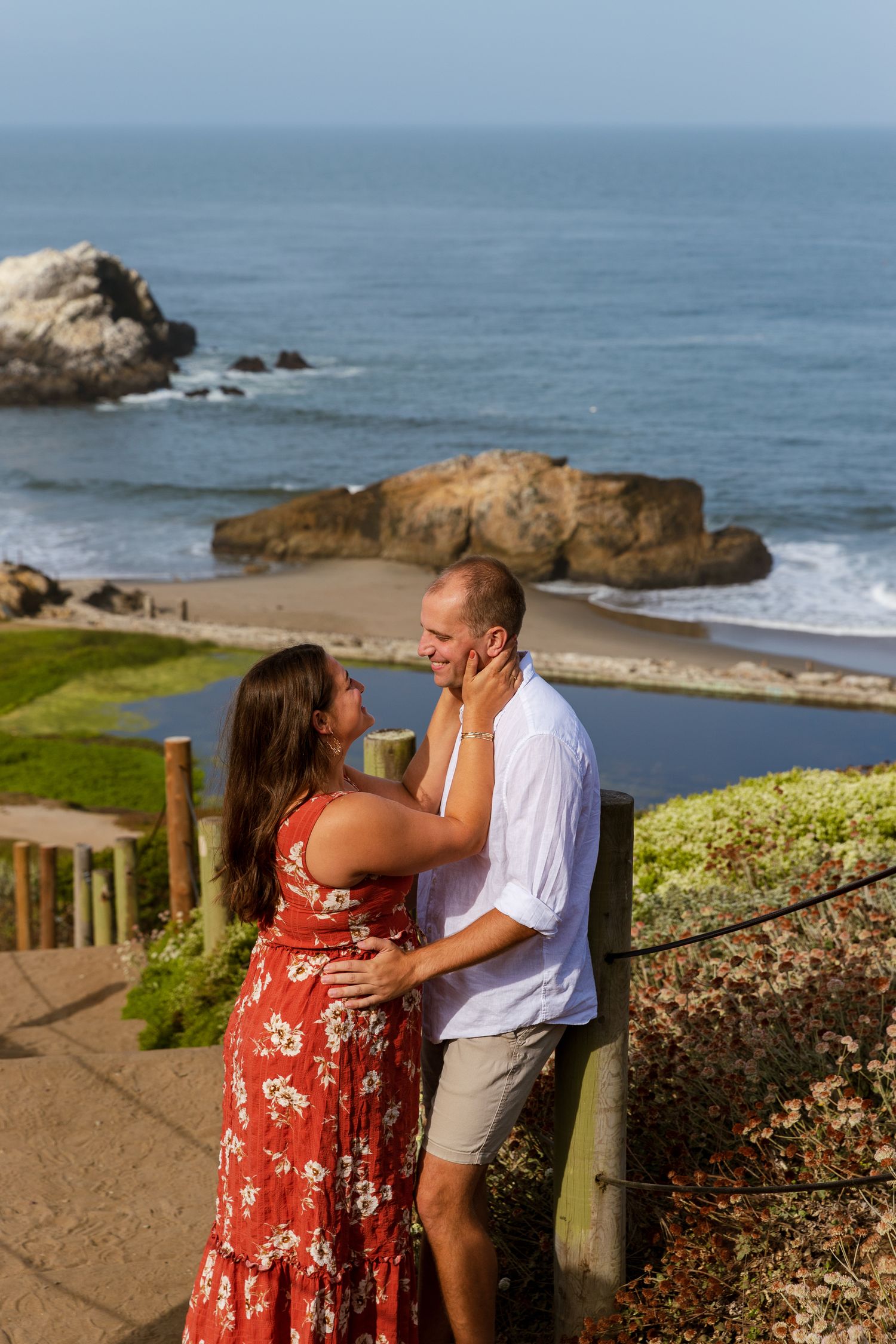 A romantic moment overlooking the Pacific Ocean at Sutro Baths in San Francisco with rocky coastline and waves in background.