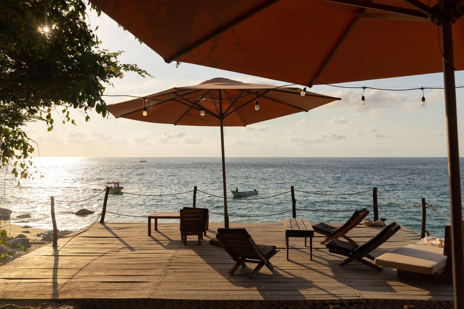 Beachside lounge chairs and umbrellas at sunset overlooking a tropical ocean view.
