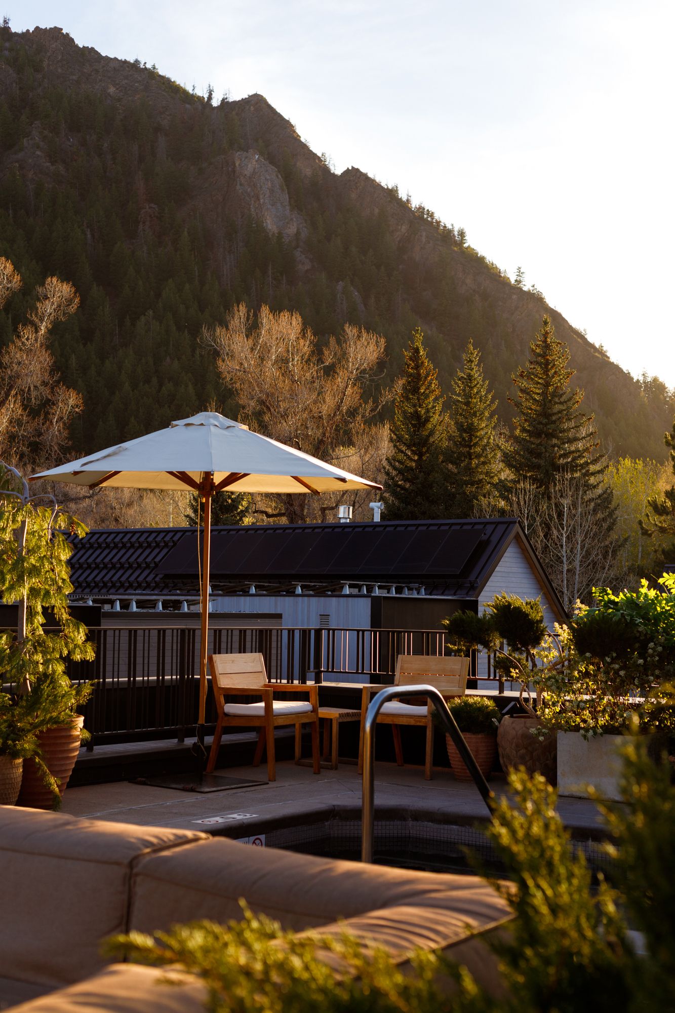 Luxury outdoor terrace with umbrella seating overlooking a scenic mountain at golden hour.