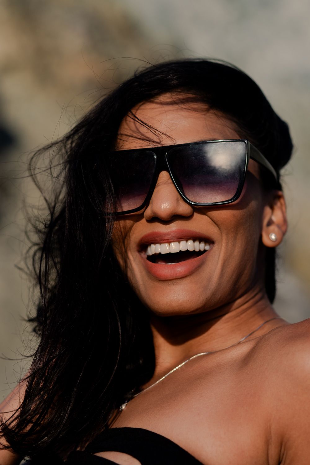 Person in sunglasses showing bright smile in warm sunlight.