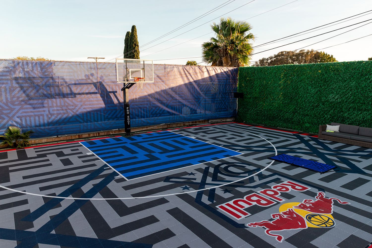 A series of maze-like patterns and sports team logos painted on an outdoor surface create a visually striking design.