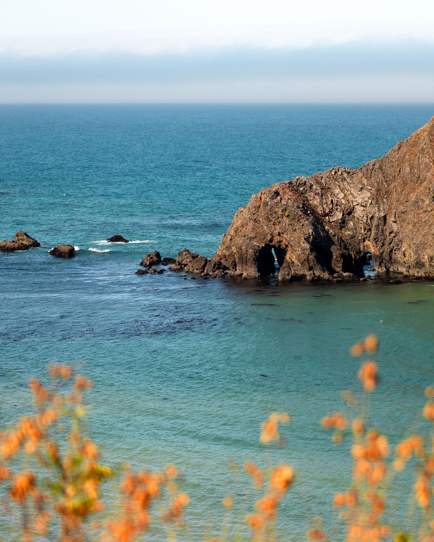Rocky coastal cliffs meet turquoise waters along a scenic Northern California beach by photographer Adrian Rudd Kahn based in Denver.