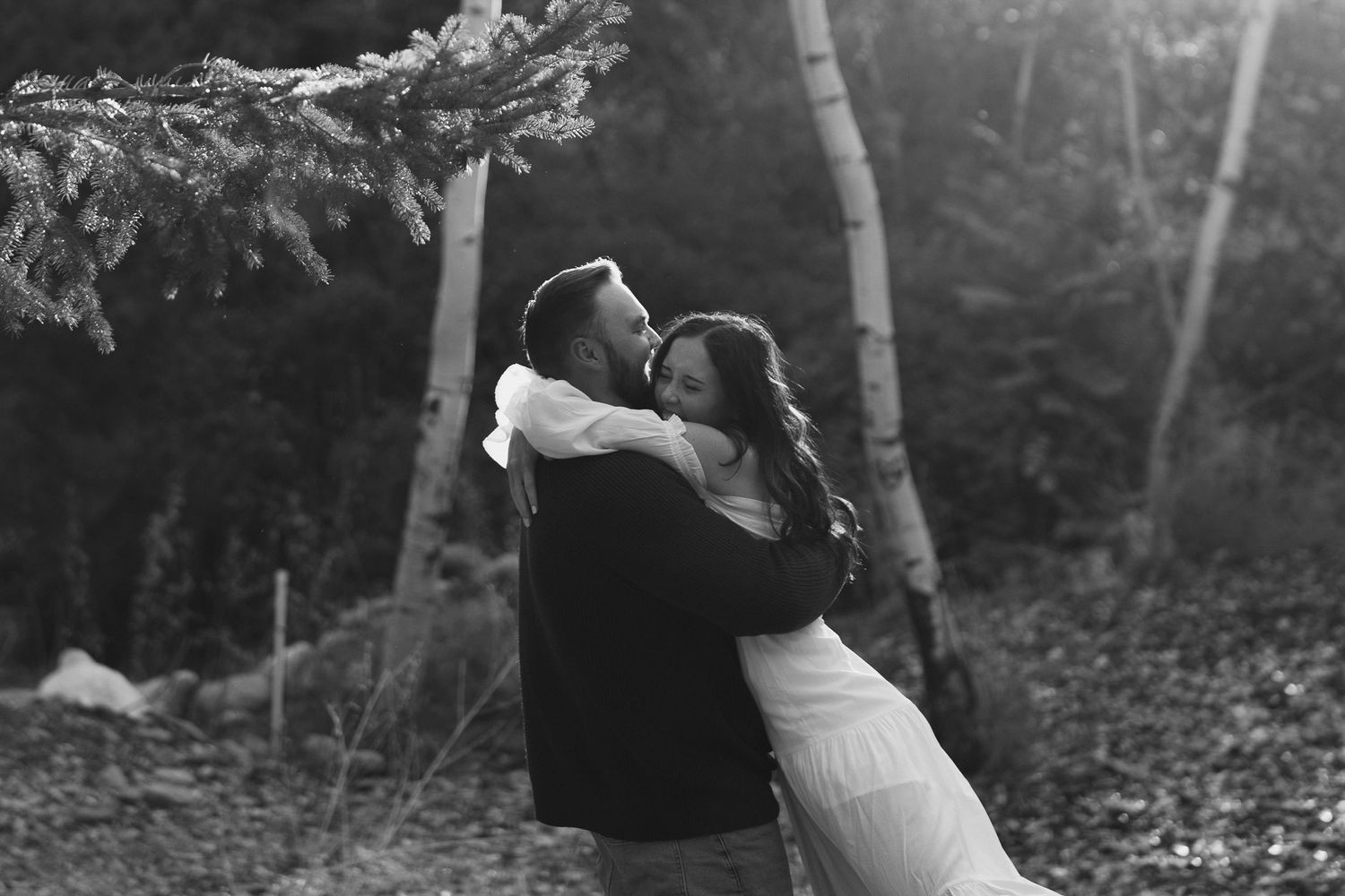 A romantic black and white photo series showing a couple embracing and dancing together in a forest setting.