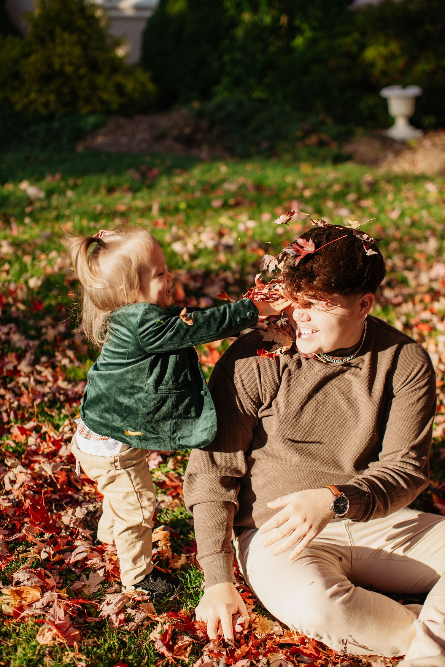 Playful moment throwing autumn leaves in a garden setting.