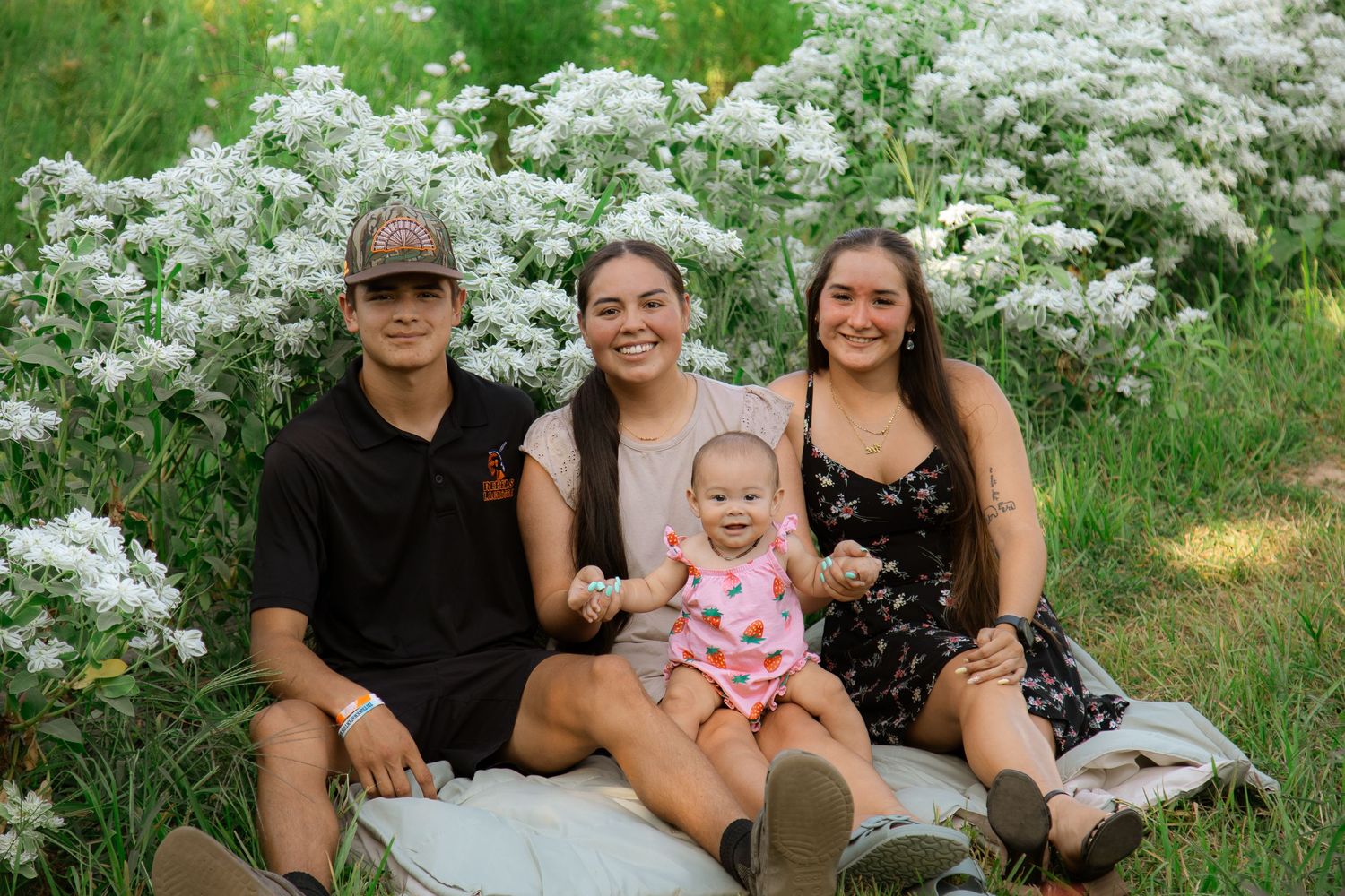 Family portrait session among blooming white flowers in a garden setting.
