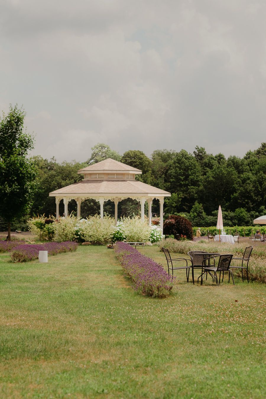 Elegant outdoor venue with gazebo and purple flowers in landscaped garden.