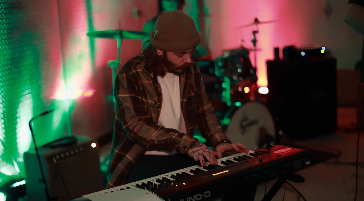 Musicians performing on stage with dramatic green and red lighting effects.