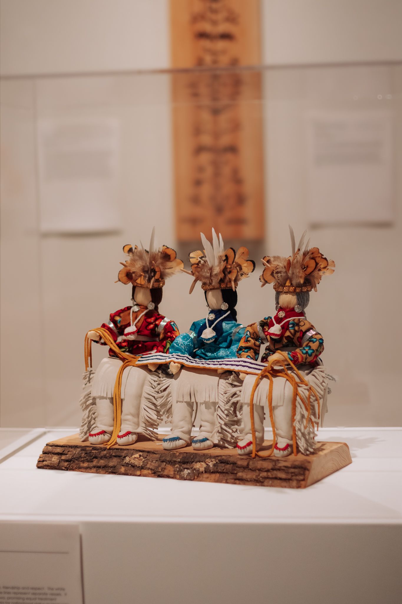 Small decorative figurines of people on horseback displayed in a museum exhibit case.