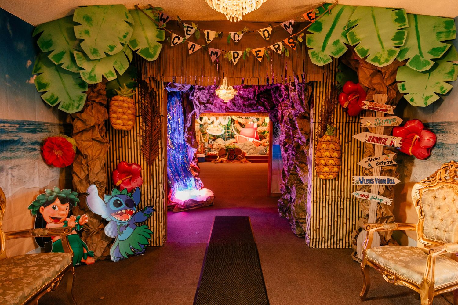 Whimsical decorated tunnel with tropical theme featuring palm trees and colorful lighting.