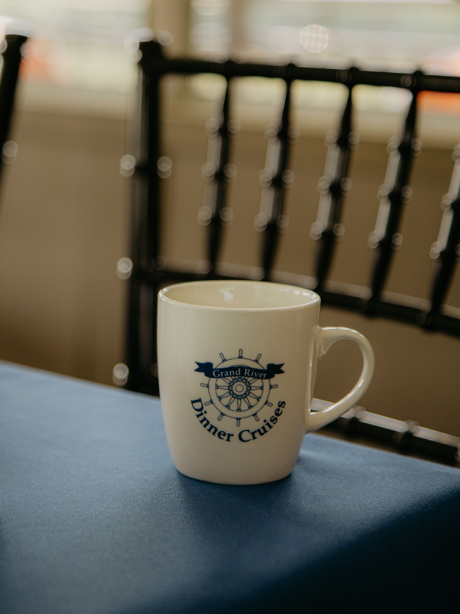 White coffee cup with a logo sits on a blue tablecloth.