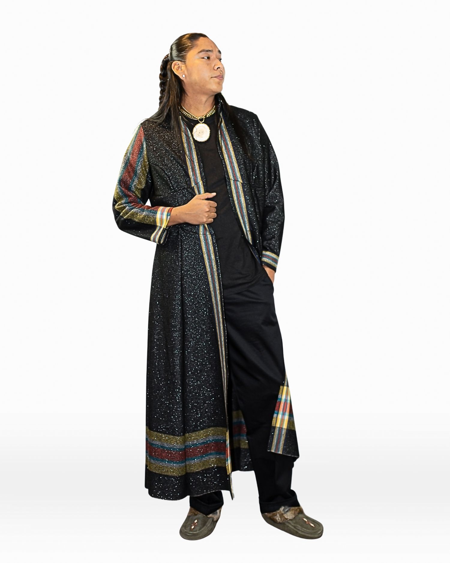 Model in long black sparkle duster coat with multicolor stripe trim over black outfit with white pendant necklace.