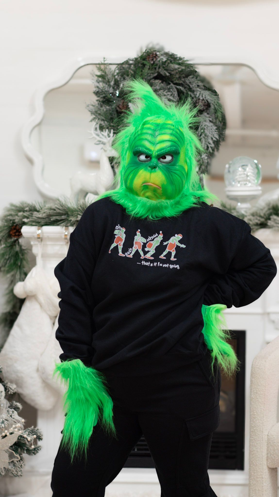 Grinch-themed black sweatshirts with festive designs displayed near holiday decorations.