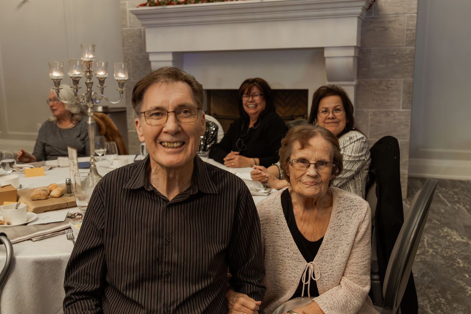 People seated at round tables during a festive holiday gathering.