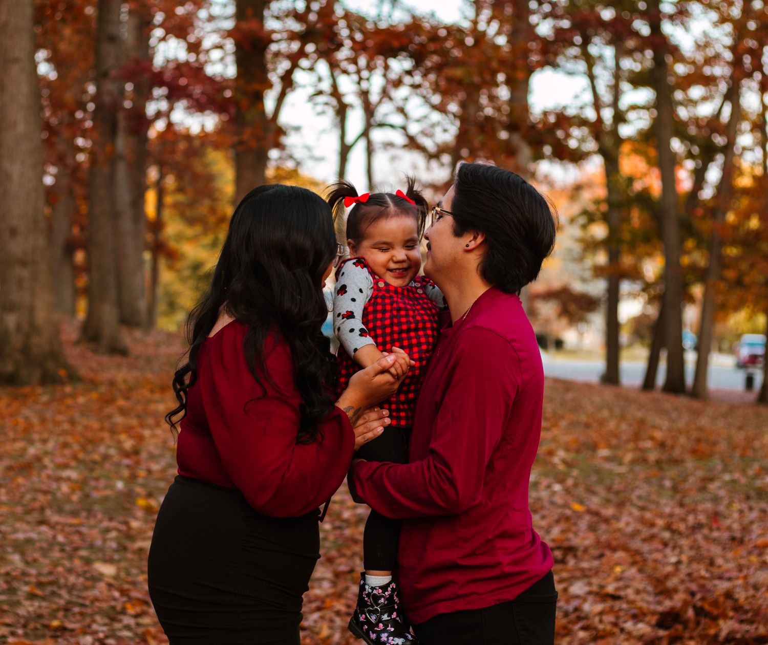 Intimate family moment captured in autumn forest setting with red clothing.
