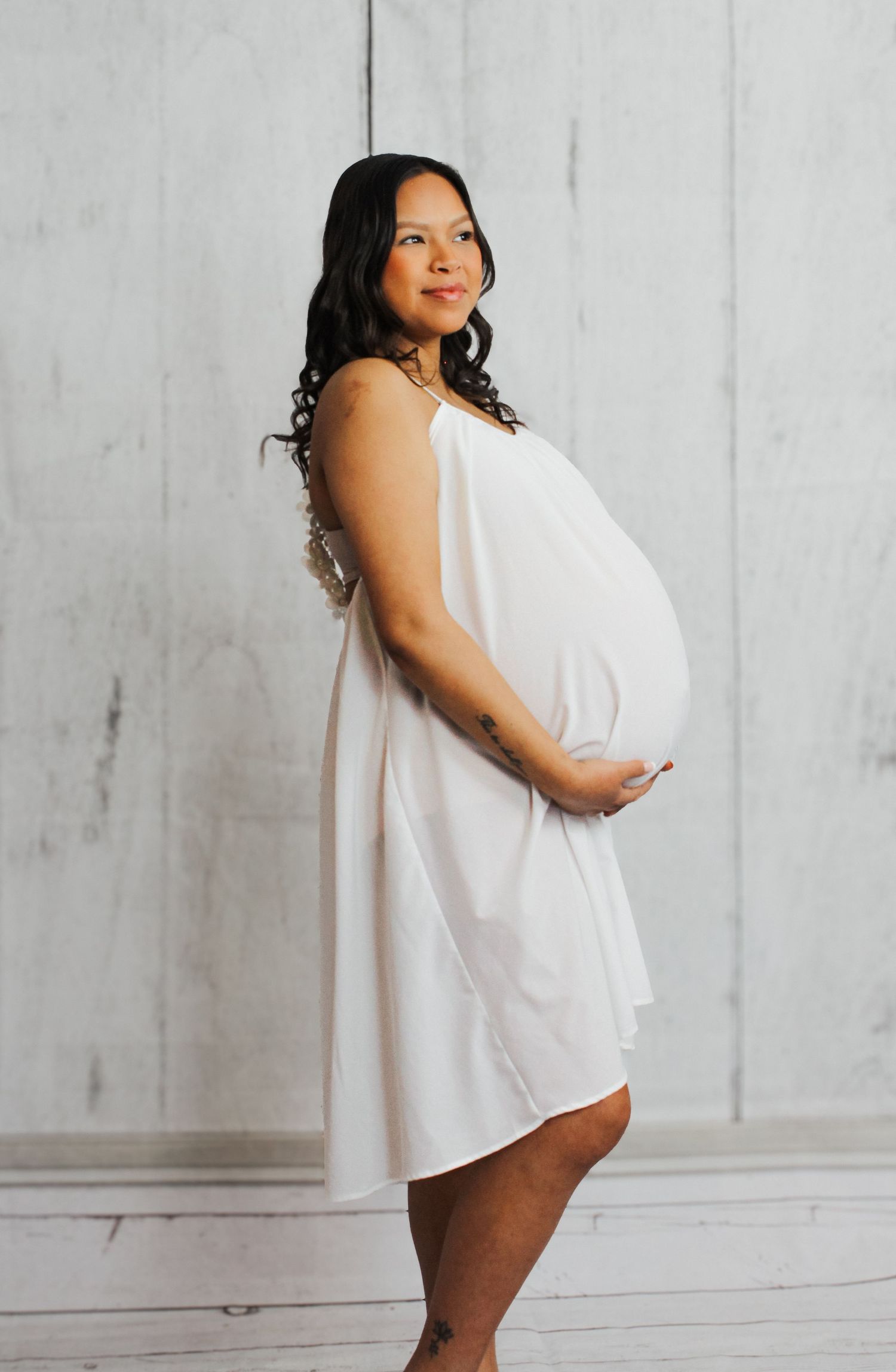 Artistic pregnancy portrait with draped white fabric in studio setting.