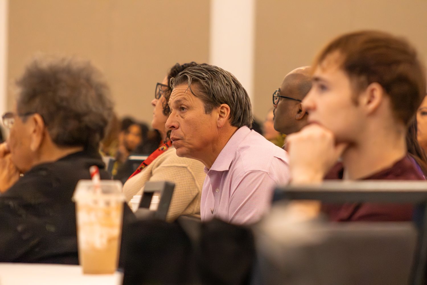 Side view of conference attendees seated in rows during a presentation.