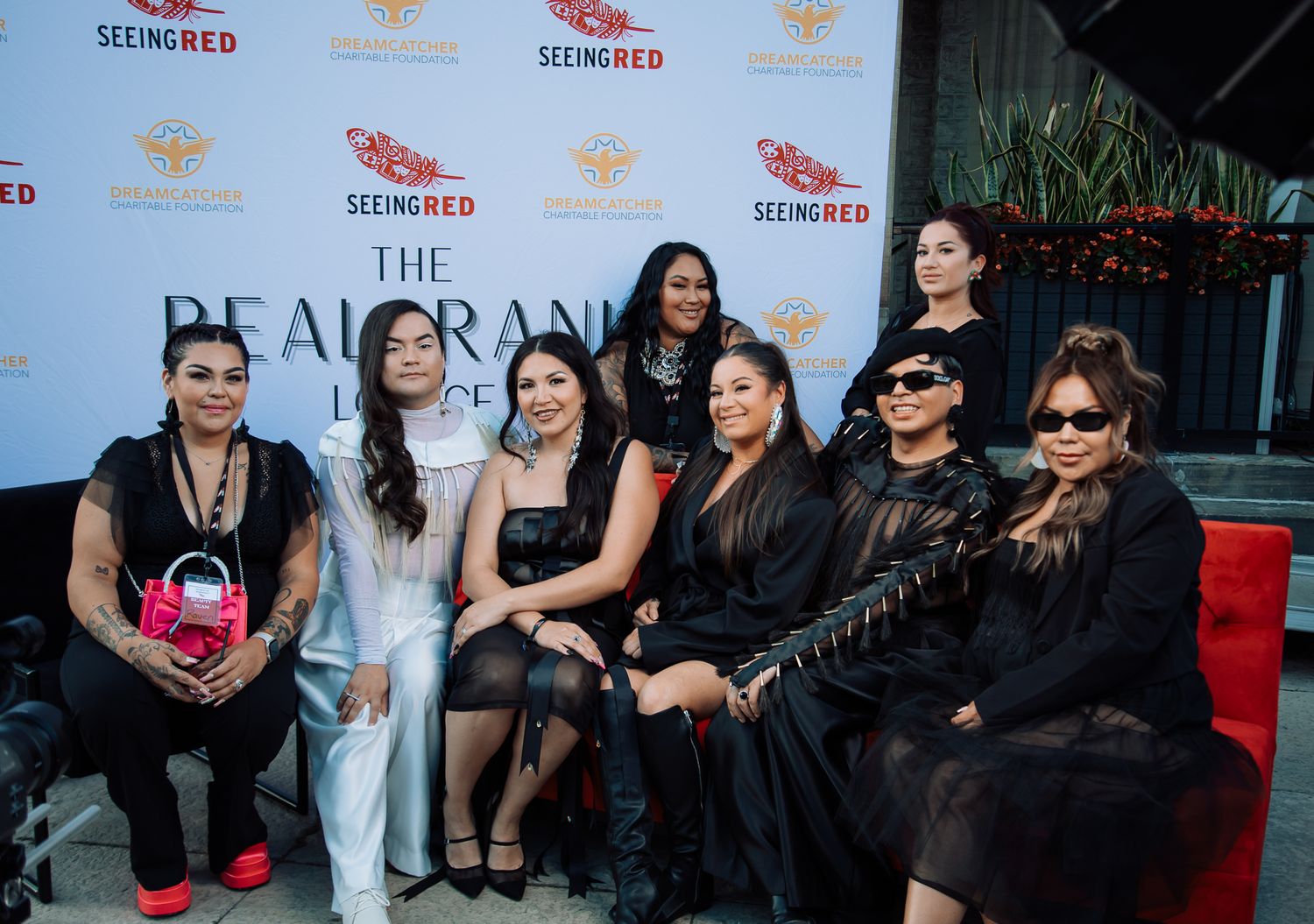Group photo of event attendees in front of branded backdrop with logos.
