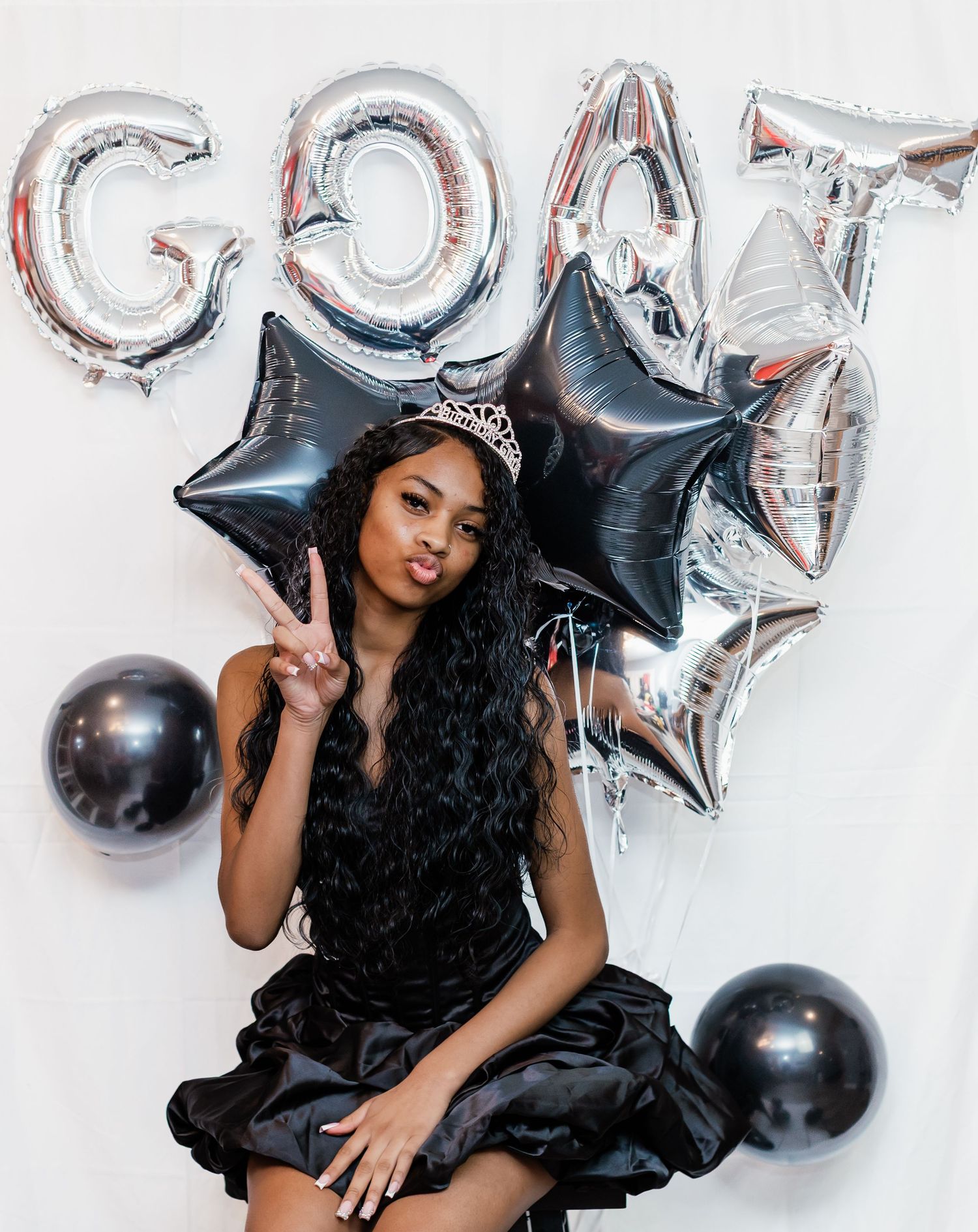 Celebratory photo setup with silver star balloons and black accents against white backdrop.
