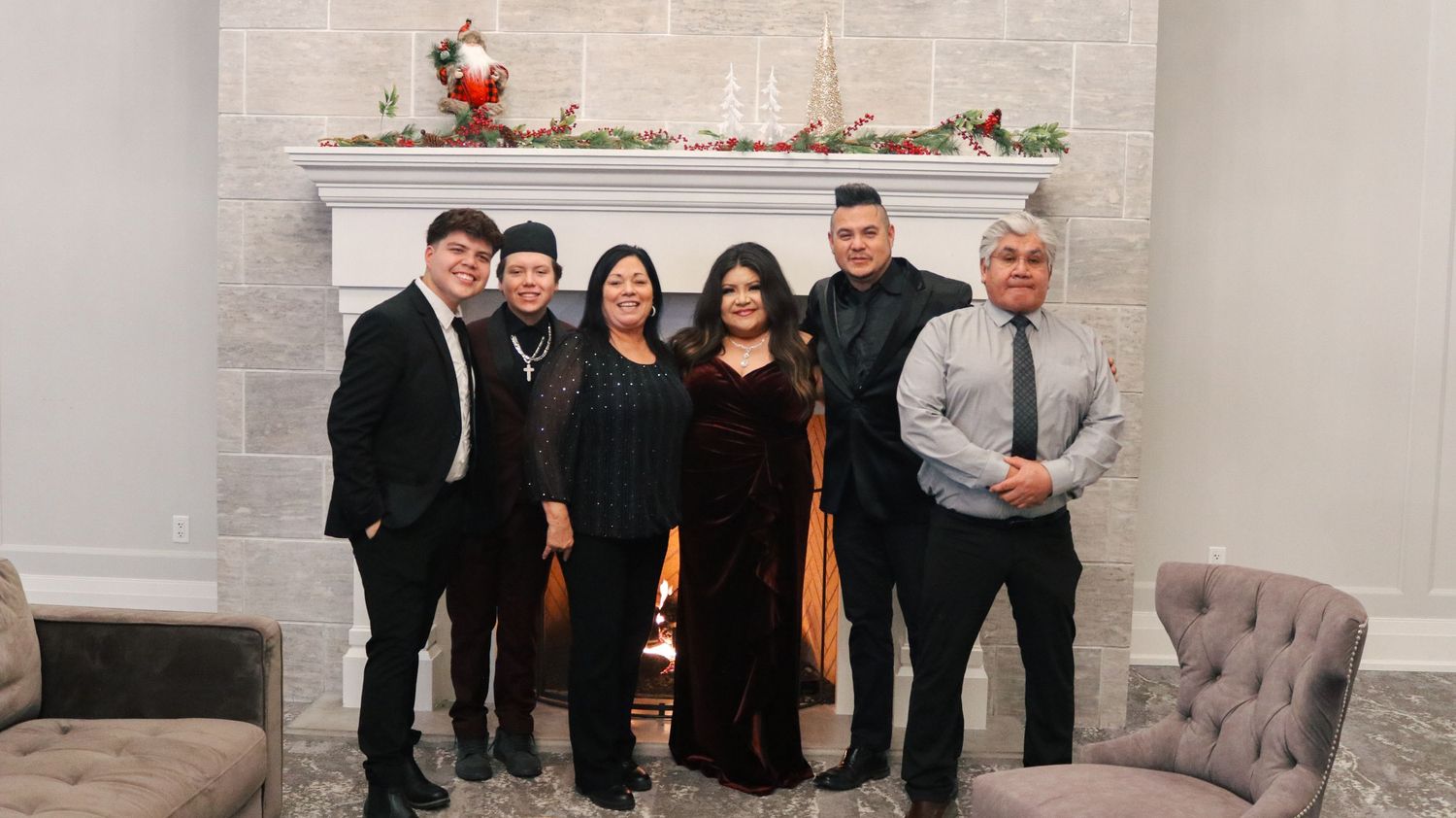 Group of people gathered in formal attire against a light colored wall at an event.