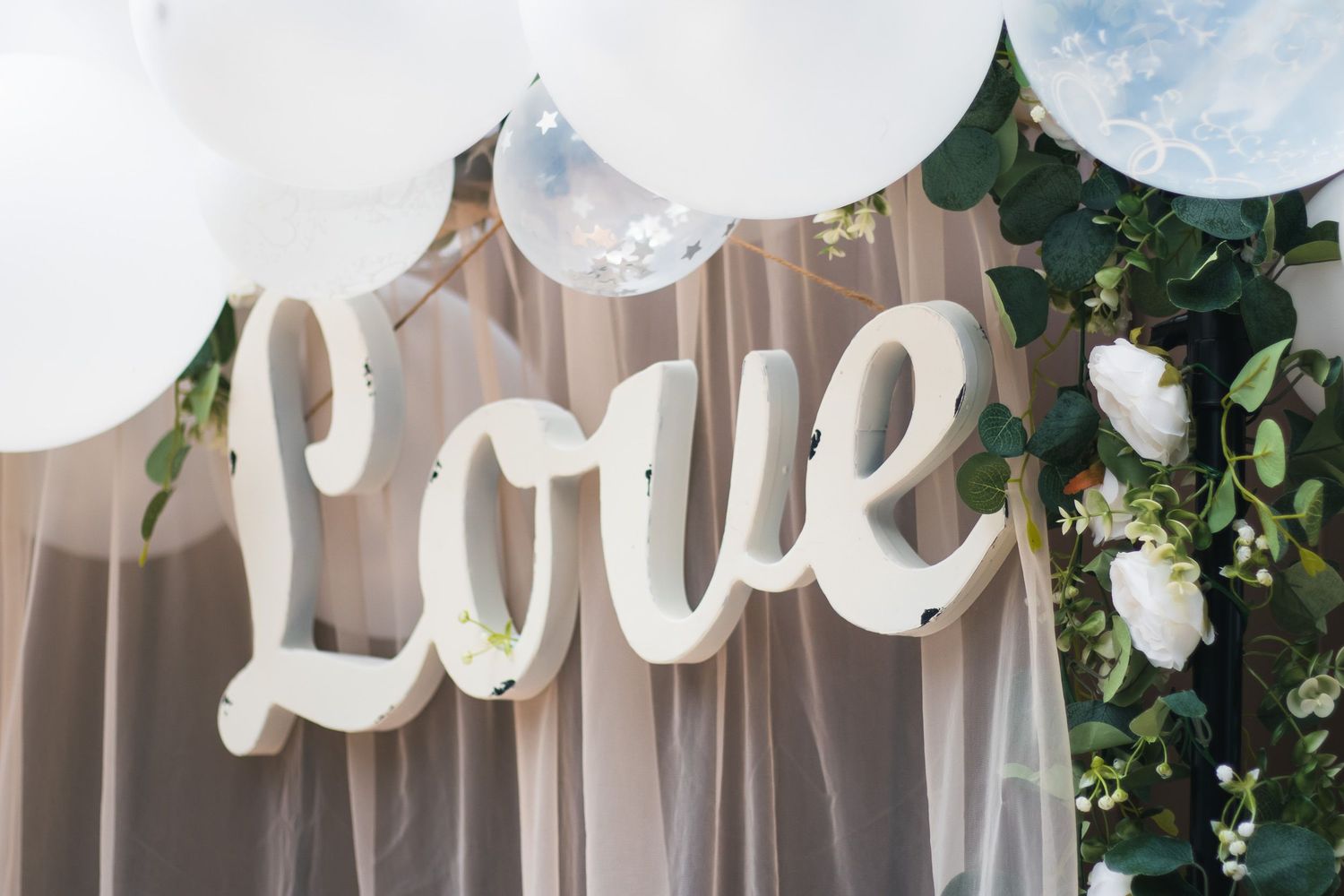 White balloon and floral decorations adorn an outdoor wedding venue.