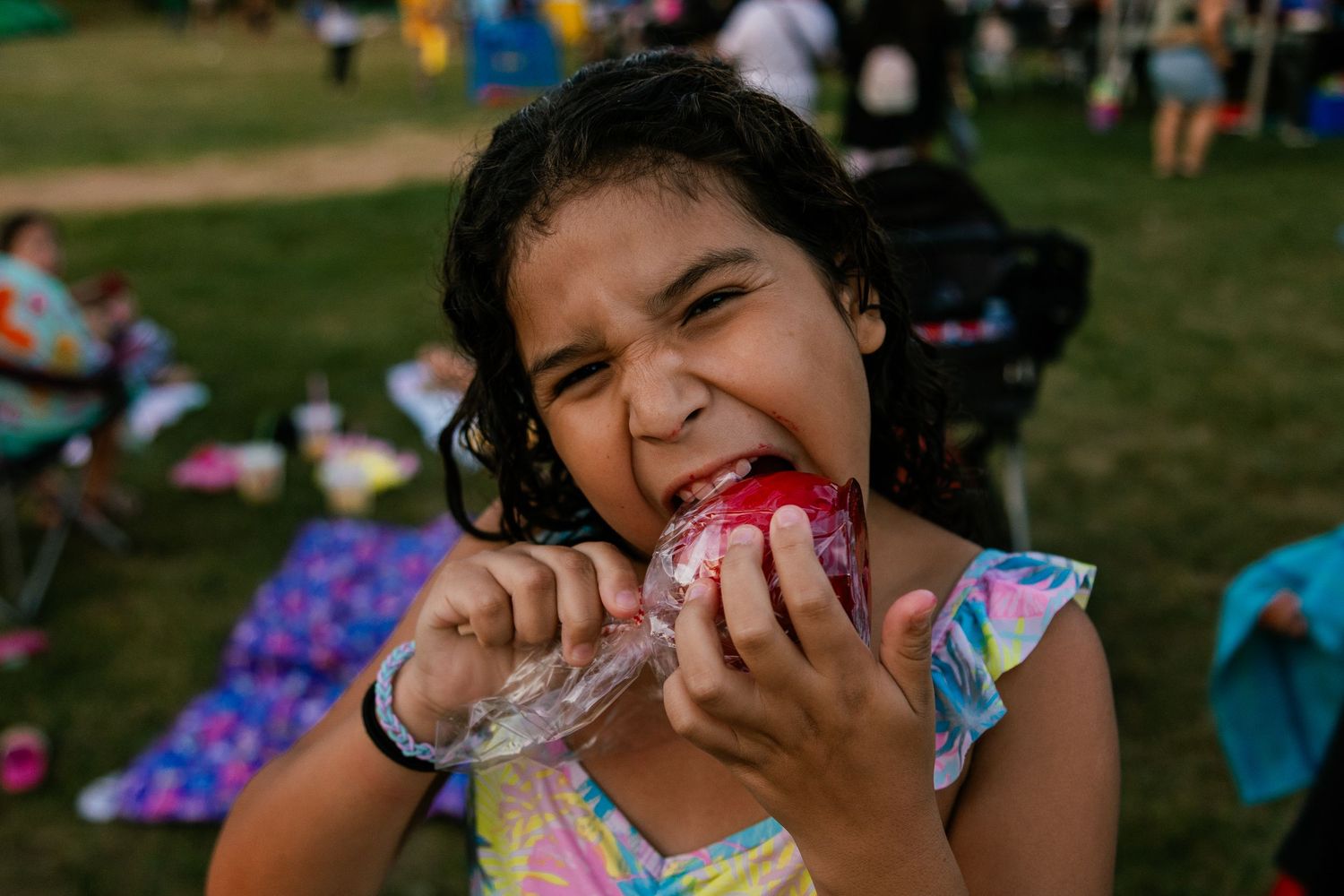 Child enjoying a pink treat at an outdoor carnival event.
