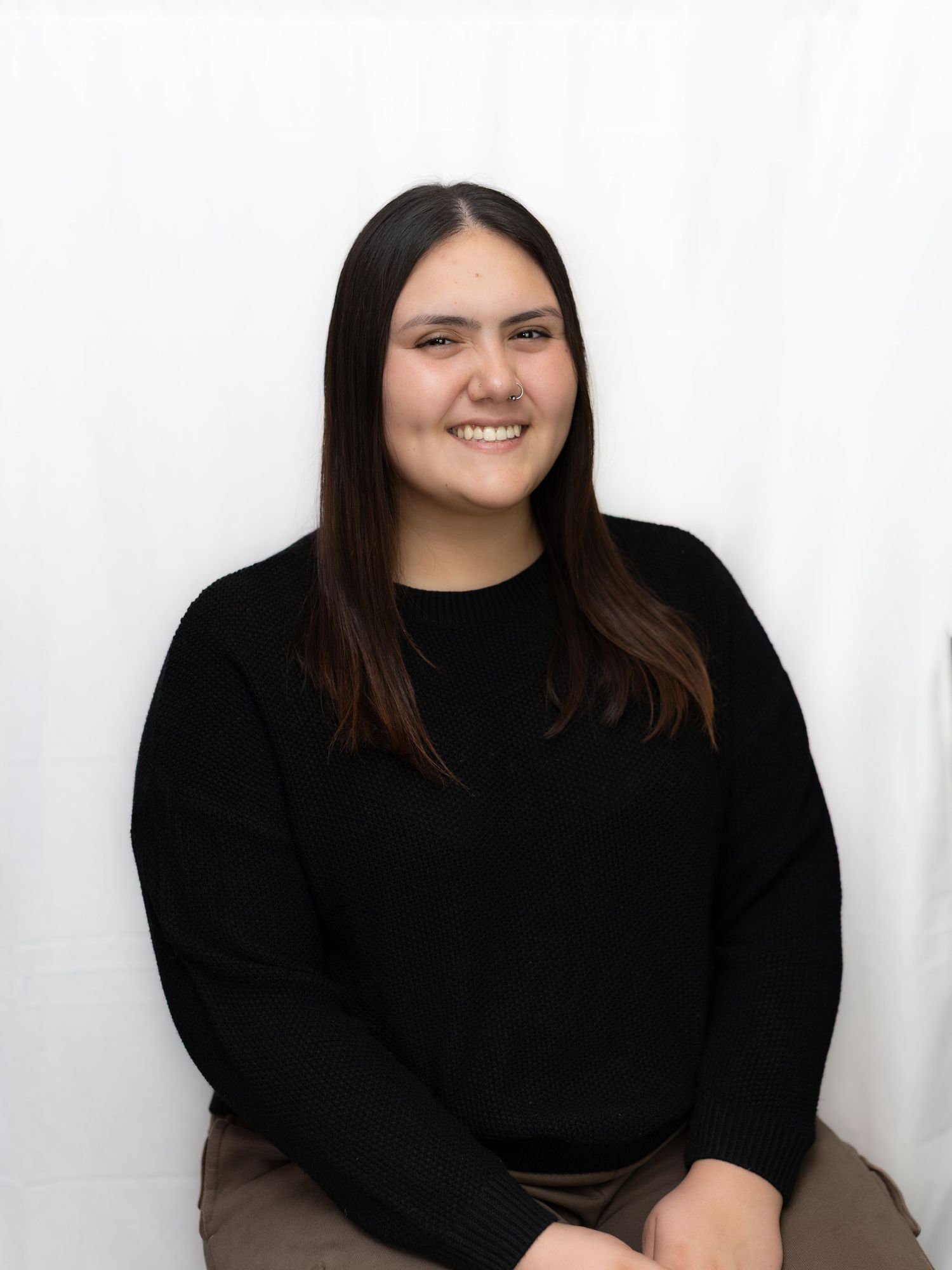 Studio portraits in black sweater against white backdrop.