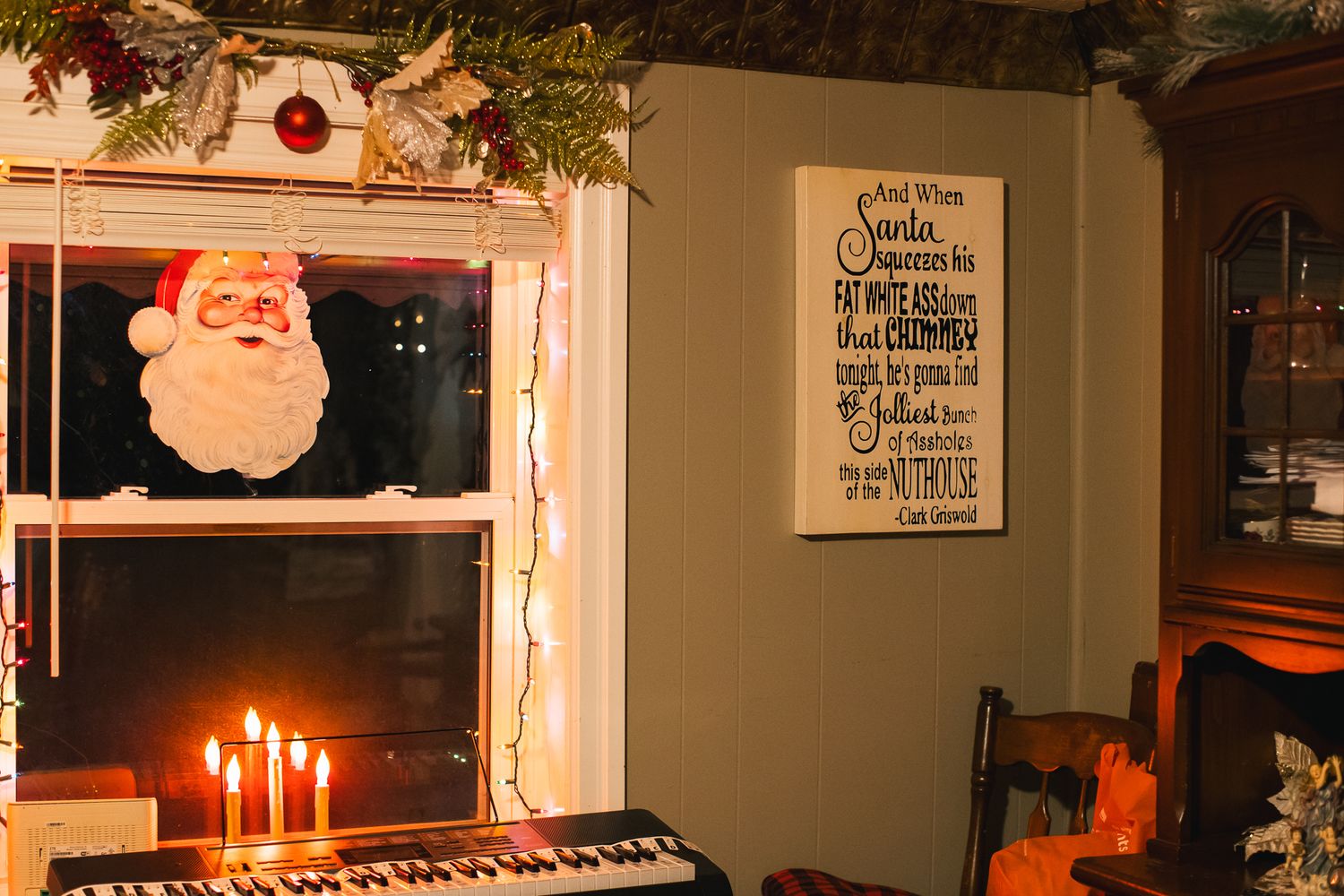 A cozy Christmas-decorated room with wooden paneling, garlands, and candlelight creating a warm holiday atmosphere.