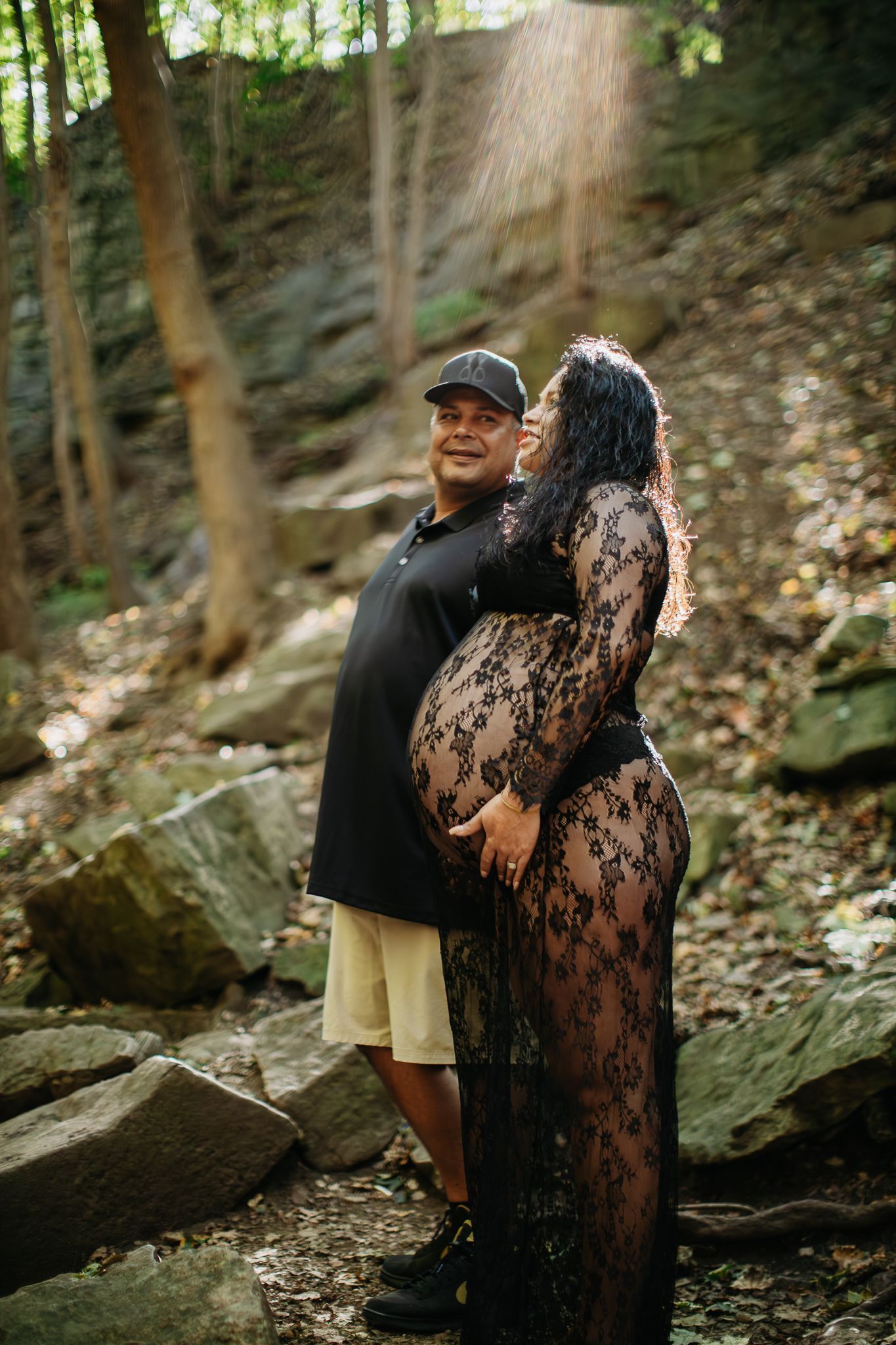 Couple posing among rocky terrain in wooded area during daytime photoshoot.