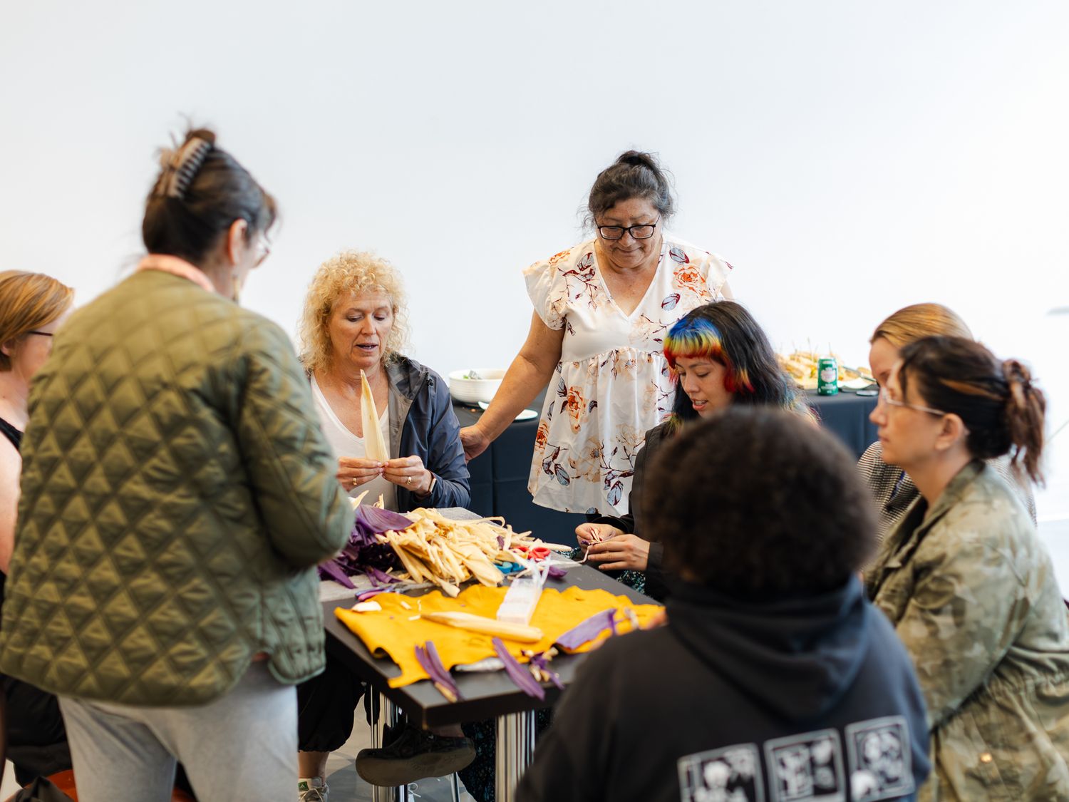 People gathered around a table crafting with colorful fabric materials during an Indigenous cultural workshop.