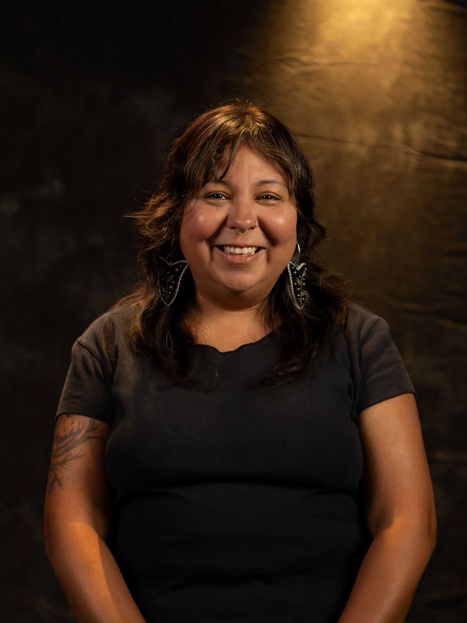 Warm studio portrait against textured dark background with dramatic lighting.