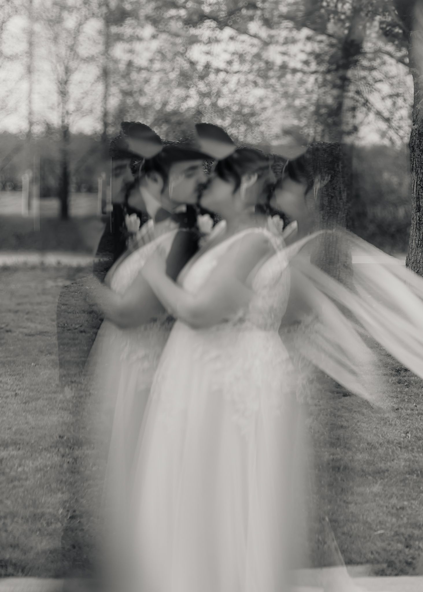 Artistic black and white multiple exposure wedding photo of couple kissing in white dress and suit.