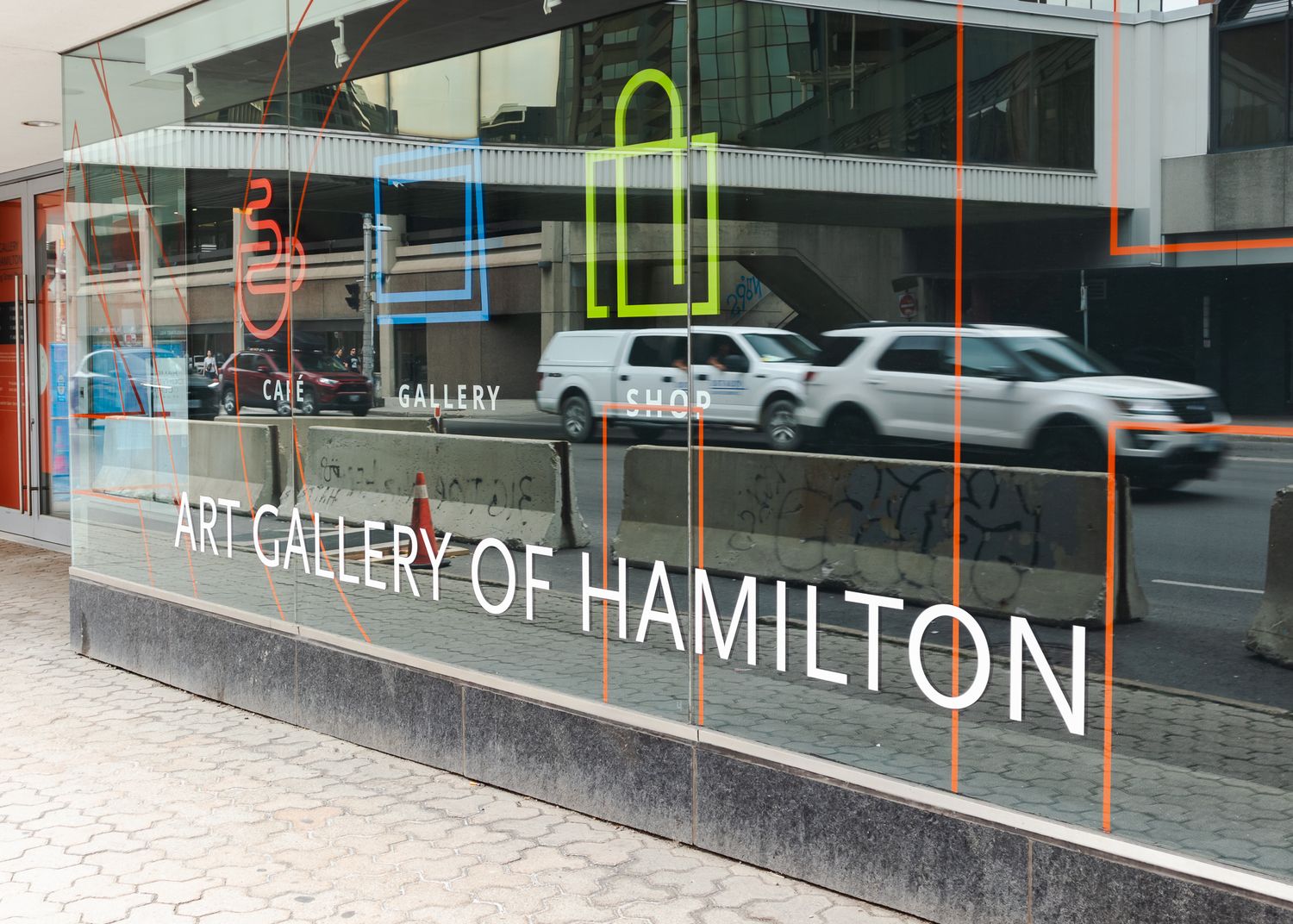 Art Gallery of Hamilton storefront with colorful logo signs displayed on large glass windows in downtown Hamilton.