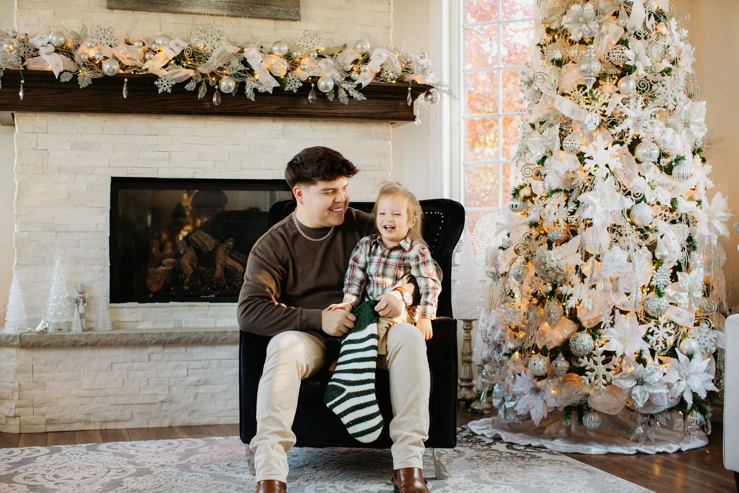Festive indoor scene with white Christmas trees and decorations against a light brick wall.