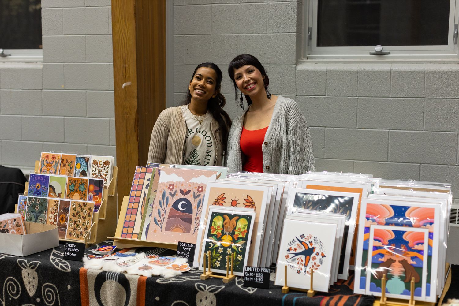 Art prints and cards displayed for sale at a local craft market.