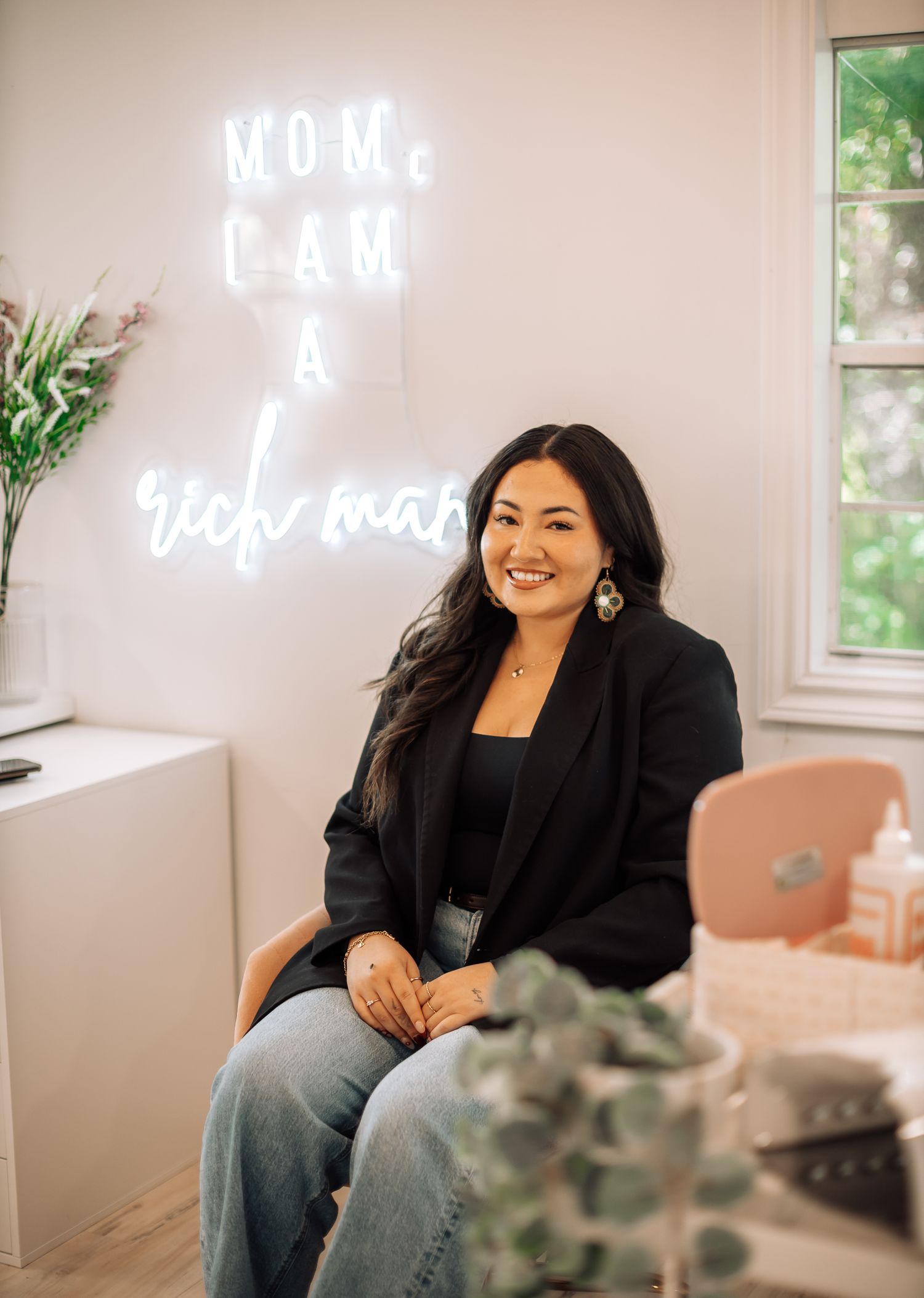 A person sits in a room with a neon sign that reads 'Mom Law & Tech Mom'.