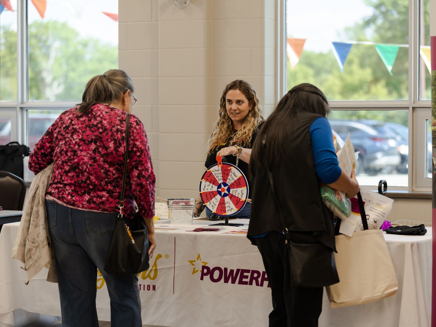 Visitors spin a prize wheel at a PowerPoint foundation booth during an indoor event.