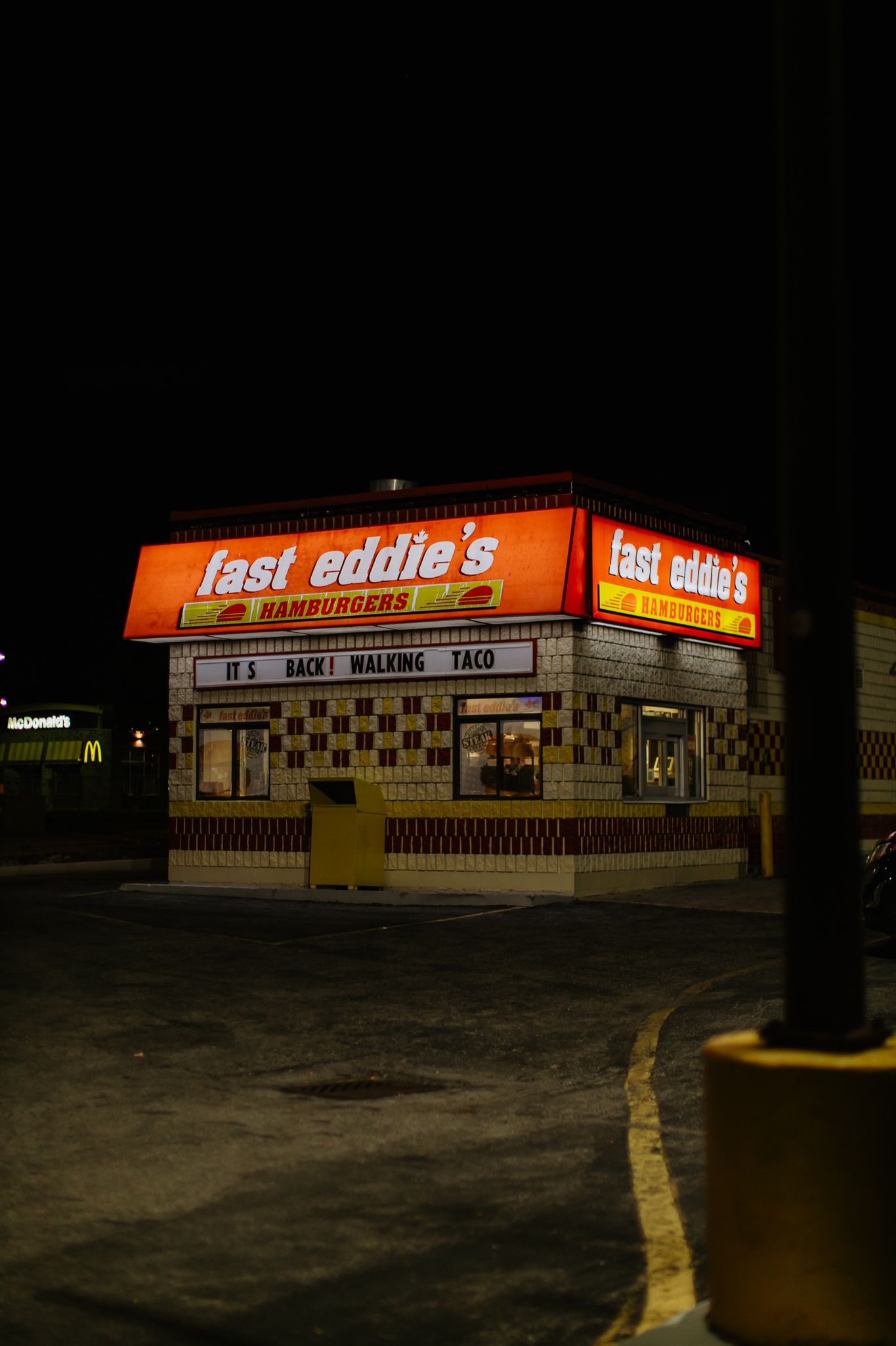 Illuminated Fast Eddie's restaurant storefront at night with empty parking lot.