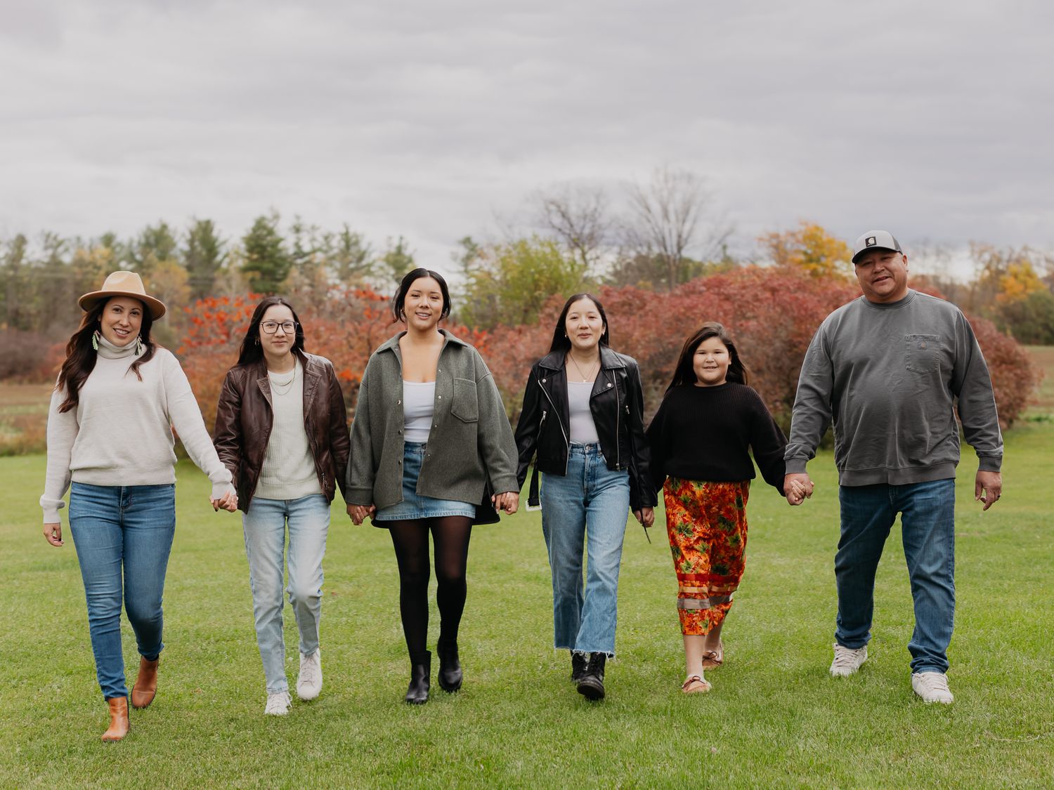 Casual group walking together across a green field on an overcast autumn day.