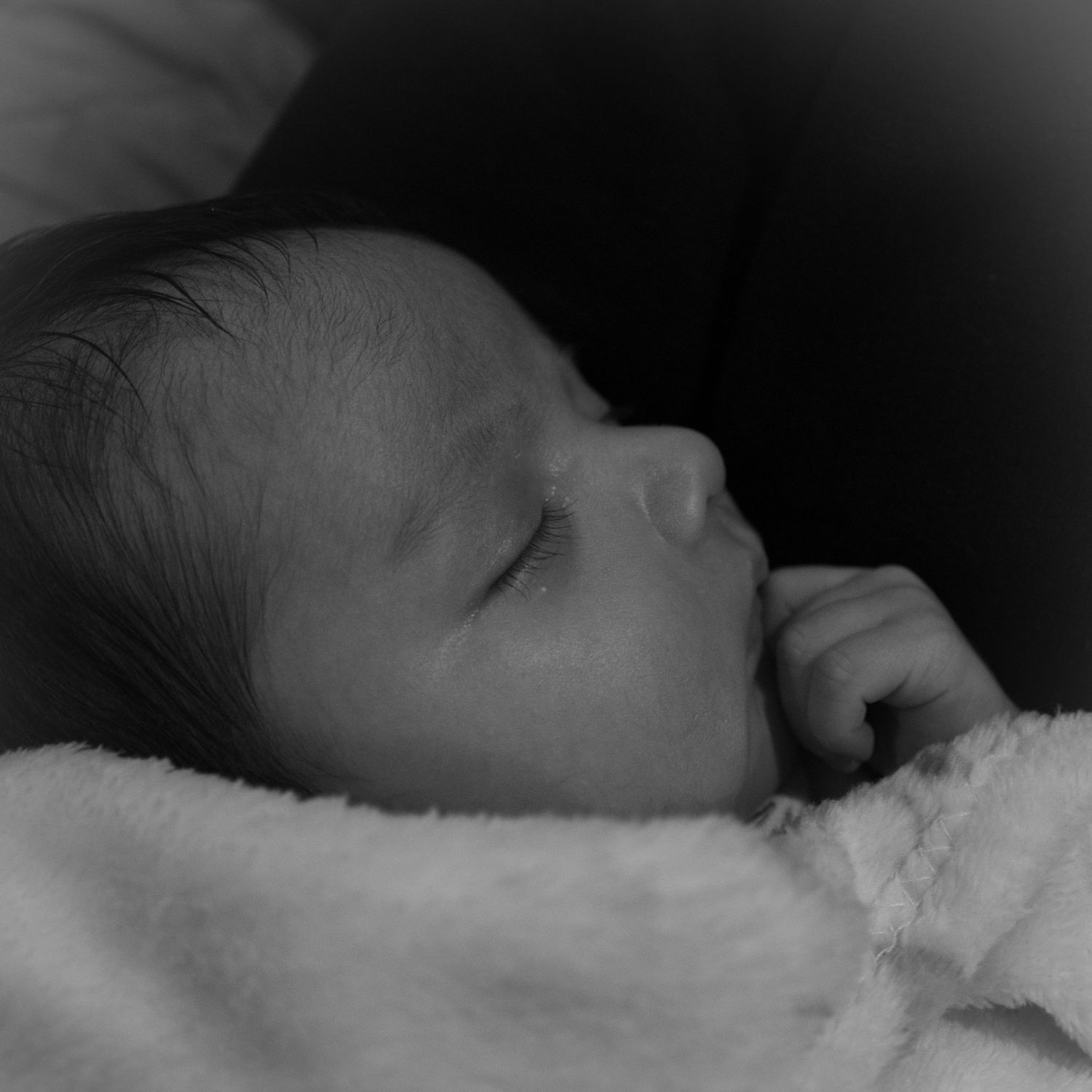 Peaceful newborn baby sleeping soundly wrapped in cozy white blanket.