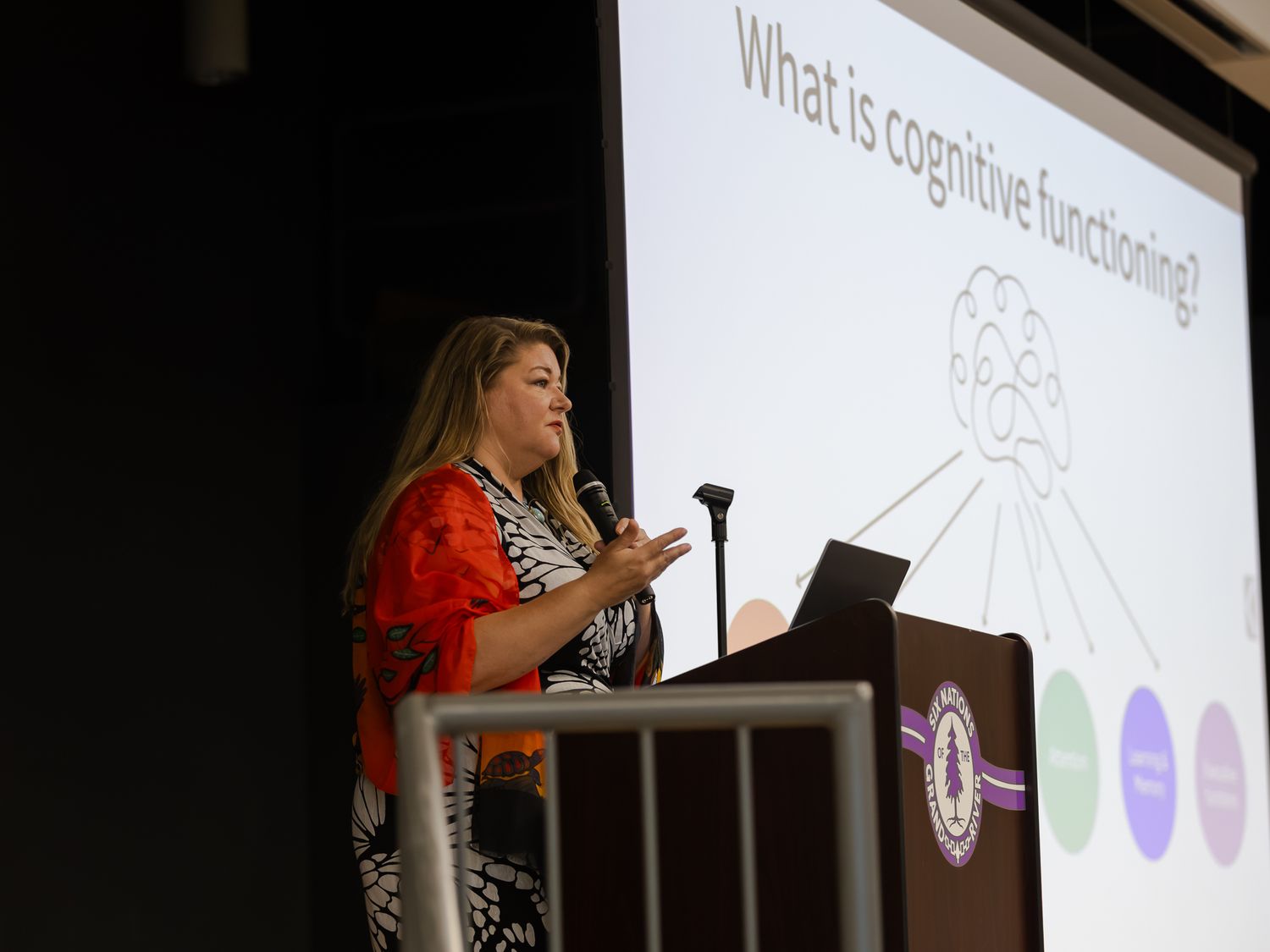 A woman presents a cognitive functioning slide at a professional conference podium.