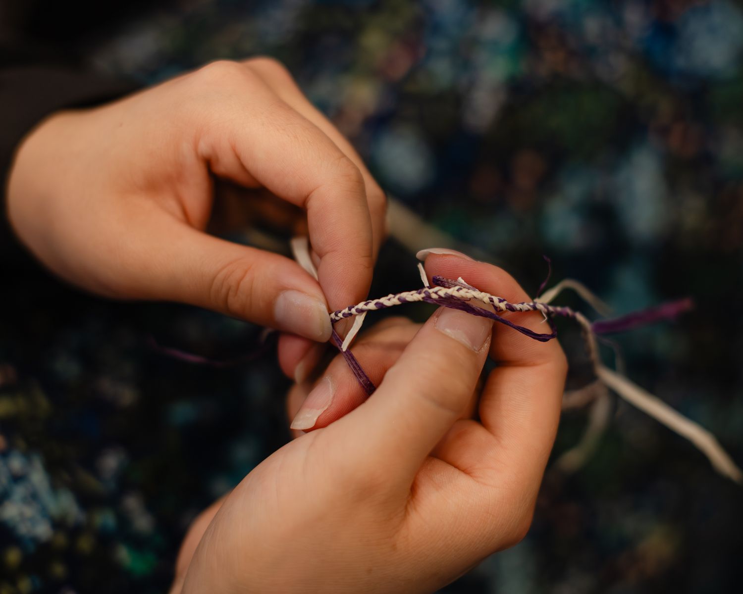 Close-up of hands braiding colorful threads to create a handmade bracelet or jewelry piece.